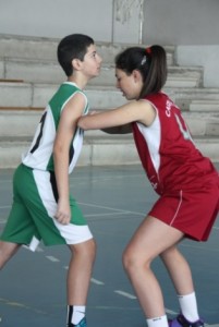 Foto de baloncesto que recoge a una niña bloqueando a un niño el rebote defensivo