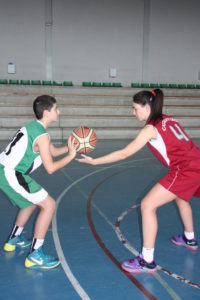 Foto de baloncesto de un niño preparado para tirar y de una niña defendiéndolo