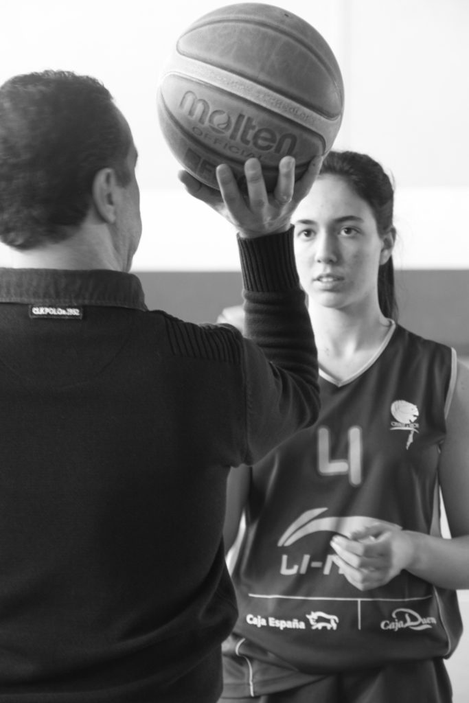 Foto de baloncesto que recoge a un entrenador y a una niña siguiendo un método para enseñar el tiro