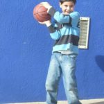 Fotografía de baloncesto que recoge a un niño jugando con un balón de baloncesto