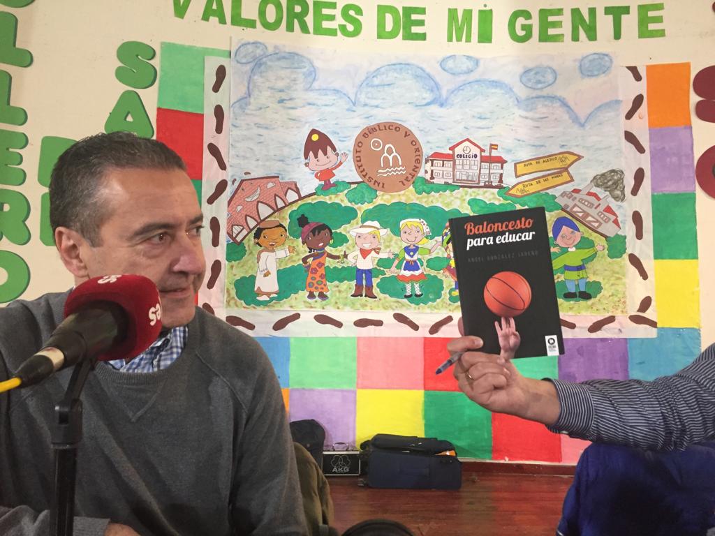 Fotografía de Ángel González Jareño con esRadio en Sabero mostrando su libro Baloncesto para educar